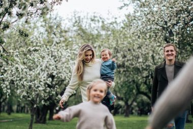 A joyful family enjoys a playful day outdoors amidst blossoming trees in spring.